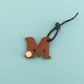 Gros plan détaillé du pendentif porte-clés lettre M en cuir PU marron avec vis en métal. - Lettre M (B422-M)