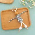 Detailed view of handmade rope woven wooden puppet keychain, creative quirky bag pendant accessory. - Blue Speckled Umbrella Rope