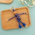 Detailed closeup shot of the handmade woven puppet keychain with colorful cord and wooden bead. - Multicolor Woven Rope