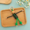 Detail view of scarecrow cord woven puppet keychain, unique handmade bag and phone pendant. - Black-Green Woven Rope