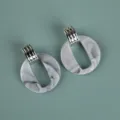 Detailed close-up of oversize grey marble acrylic earrings with silver metal connector. - Exaggerated Geometric Hoop / Two-Tone White