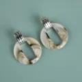Detailed close-up view of oversized acrylic marbled hoop earrings with metallic top styling. - Exaggerated Geometric Hoop / Two-Tone Beige