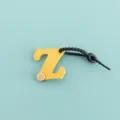 Vue détaillée du charm de sac lettre Z en cuir PU jaune avec cordon noir et bouton. - Lettre Z (B422-Z)