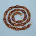 Detailed close-up of brown tortoiseshell acrylic chain with gold clasps for bags or phones. - Coffee