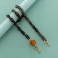Close-up detail of stylish resin acrylic bag chain with amber lantern bead and gold clasps. - Light Gray