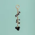 Close-up detail of luxury black and clear resin beads with gold chain bag charm keychain. - B386-6