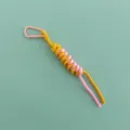 Detail shot of a stylish woven bag charm featuring a pink carabiner and yellow rope. - Pink