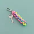 Detailansicht des bunten geflochtenen Nylonseil-Taschenanhängers mit Metallbeschlägen. - Regenbogen