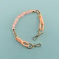 Close-up detail of the pink heart bead and gold metal chain phone strap accessory. - Pink Heart Resin Chain