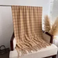 Detailed shot of retro plaid tassel shawl on chair, warm autumn style cozy texture accessory - Camel