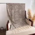 Close-up view of a cozy brown paisley patterned cashmere-feel shawl with elegant fringe details. - Light Gray