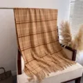 Detail shot of cozy plaid cashmere feel tassel shawl scarf texture and pattern closeup - Camel