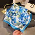 Detailed view of blue and white floral silk scarf with solid blue border, elegant styling. - 66-70cm / Blue