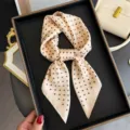 Vista dettagliata di un elegante foulard quadrato in seta con pois, classico accessorio. - Beige