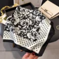 Detailed view of black and white silk square scarf with elegant rose print and polka dot border. - Black