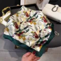 Close-up view of a vibrant botanical print silk square scarf with a chic dark green border. - Green