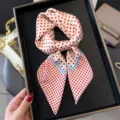 Detailed shot of a stylish white silk scarf featuring red polka dots and elegant blue borders. - Khaki