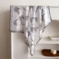 Detailed shot of a black and white floral print imitation silk square scarf draped gracefully. - Black Edge