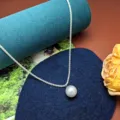 Dettaglio in primo piano della collana con ciondolo di perla e catena scintillante. - Perline artificiali