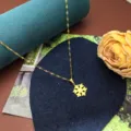 Close-up detail shot of the elegant gold snowflake pendant necklace on a decorative display pad. - Snowflake Necklace / Gold
