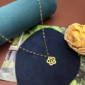 Vista di dettaglio della collana con ciondolo floreale dorato e catena delicata. - Collana con fiore di rosa / Oro