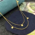 Dettaglio in primo piano dell'elegante collana geometrica a doppio strato con ciondoli quadrati. - Collana di Piccole Perline Quadrate