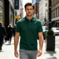 Vue détaillée du polo vert élégant pour homme porté par un modèle marchant à l'extérieur. - Vert Foncé