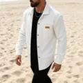 Detailed shot of men's white waffle textured long sleeve shirt with chest pocket on beach. - S / Tops / White