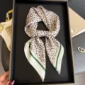 Gros plan détaillé d'un foulard en soie à imprimé léopard chic avec bordure verte sur plateau noir. - FG334-4