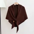 Close-up detail of soft brown knitted shawl showing textured fabric and small leather tag. - Dark Red