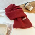 Detailed view of the cozy red knit scarf, showing soft woolen texture and label. - Dark Red