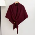 Burgundy knitted shawl detail, cozy winter triangular scarf hanging on wooden hanger. - Burgundy