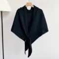 Gedetailleerde close-up van een comfortabele zwarte gebreide driehoekige sjaal op hanger. - Zwart