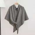 Detail van grijze wollen gebreide sjaal met zachte textuur, warme driehoekige wikkelstijl. - Grijs