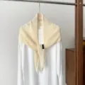 Detailed view of the cream hollow knit triangular shawl scarf hanging on a wooden hanger. - 145*42cm / Off White