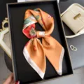 Detailed close-up of a stylish orange floral silk square scarf, perfect for elegant neck wear. - Orange