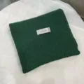Detailed view of the solid green knitted scarf, showing soft texture and neat stitching. - Green