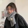 Detailed view of a cozy grey knitted scarf with cable knit texture, perfect for winter warmth. - 11