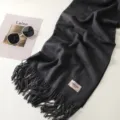 Dettaglio di sciarpa invernale spessa grigio scuro, morbida trama e frange eleganti. - Grigio nero