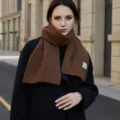 Close-up detail of the cozy brown knitted winter scarf, showing fine texture and soft fabric. - Coffee / 160