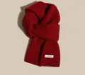Red wool knit scarf detail view, cozy winter neck warmer with 100% wool material label. - Red