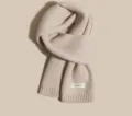 Detailed view of soft beige knitted wool scarf, classic winter warm neck accessory for women. - Off White