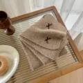 Detailed view of the cozy wool blend knitted neckerchief featuring cute black ribbon accents. - Camel