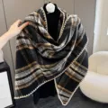 Detailed view of the cozy black and brown plaid triangular shawl with knitted edge trim. - Black