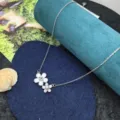 Primo piano della delicata collana con ciondolo a doppio fiore in smalto bianco e zircone. - Collana Floreale Bicolore / Argento