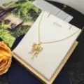 Primo piano dettagliato della collana con fiocco dorato e zirconi scintillanti su espositore. - Collana con Farfalla Cava / Oro