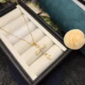 Primo piano di una delicata collana con ciondolo a croce placcata in oro esposta in un portagioie. - Collana con croce / Oro