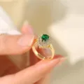Dettaglio ravvicinato di un anello dorato con pietra verde a pera e alone di zirconi. - Oro - Anello Aperto a Goccia Smeraldo