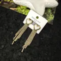 Primo piano dettagliato di eleganti orecchini a perno con nappine in pietre preziose. - Orecchini a Bottone con Nappa a Cuore di Conchiglia / Oro