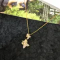 Primo piano dei dettagli della collana con ciondolo in zircone a farfalla doppia dorata. - Collana Fiore di Quadrifoglio Grande e Piccolo / Oro